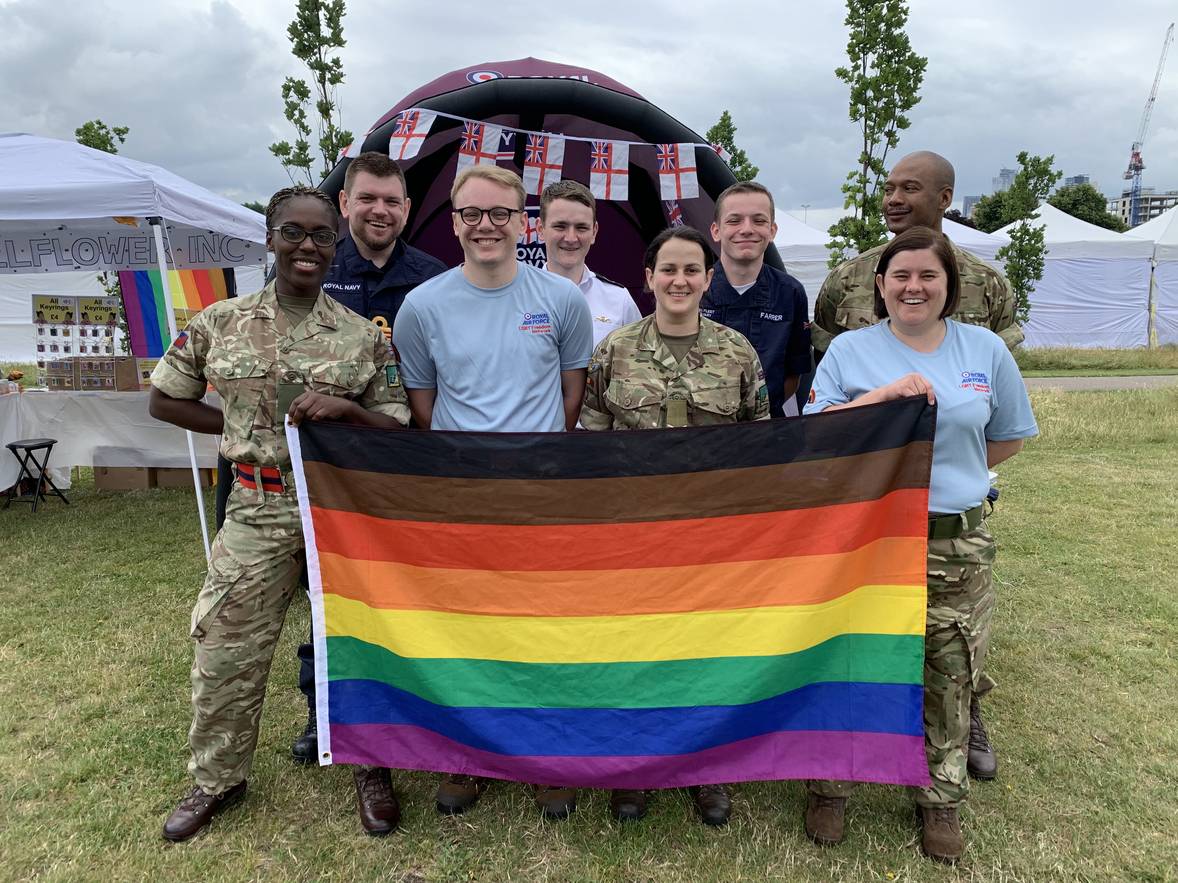 Personnel stand with Pride flag. 